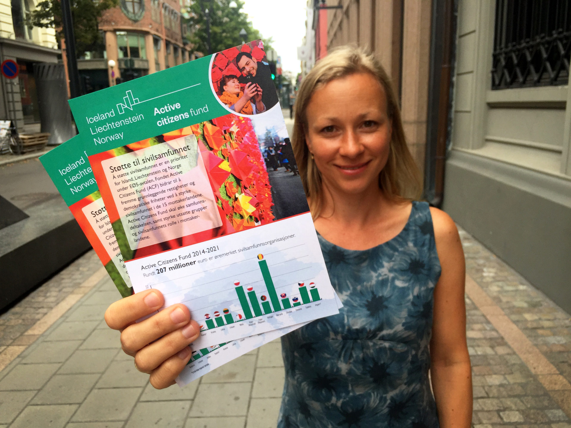 Kvinne fra sivilsamfunnet holder opp flyers om Active Citizens Fund
